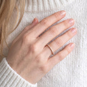 Woman wearing DEMAIN Diamonds 14k rose gold eternity band ring set with lab grown diamonds on ring finger - lifestyle view