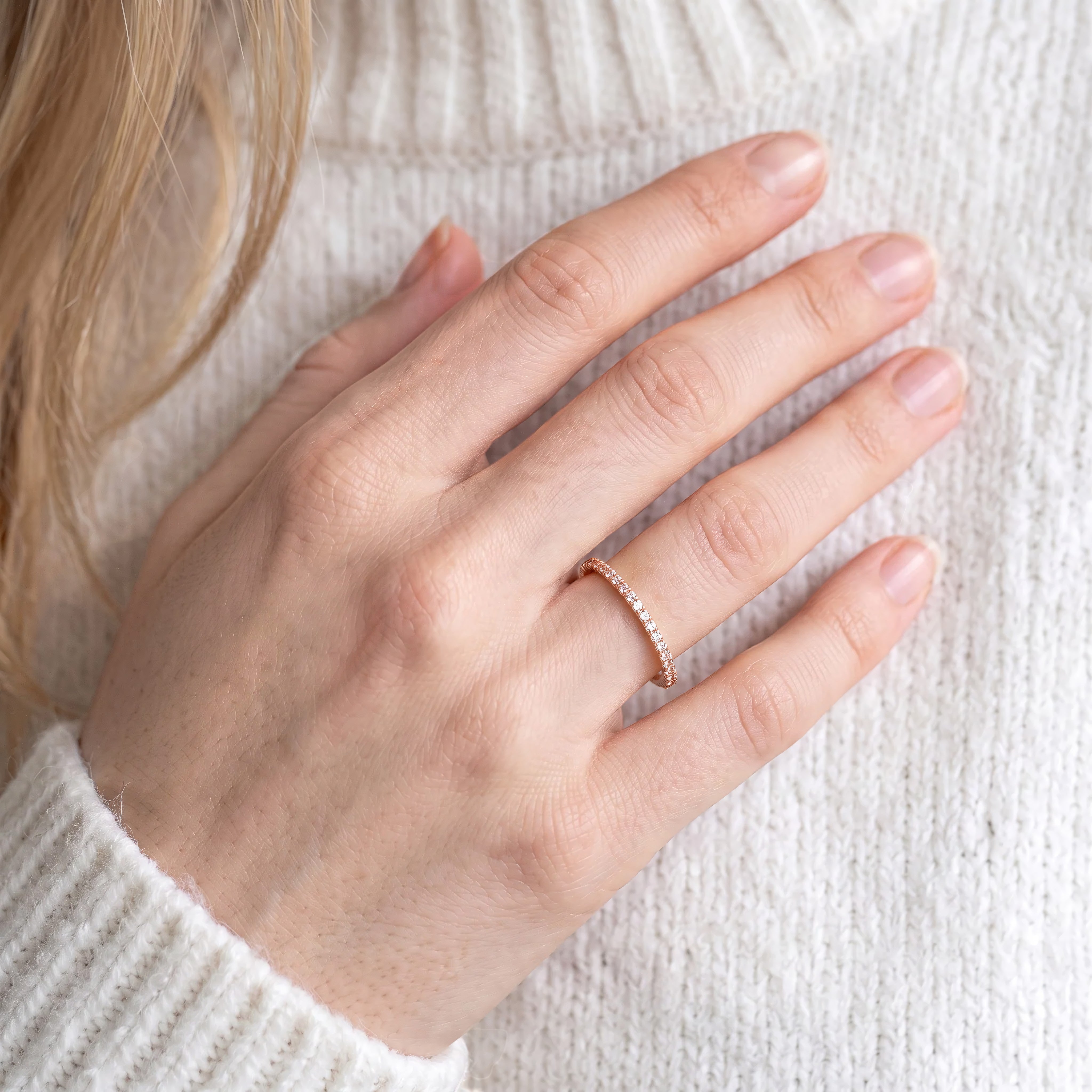 Woman wearing DEMAIN Diamonds 14k rose gold eternity band ring set with lab grown diamonds on ring finger - lifestyle view