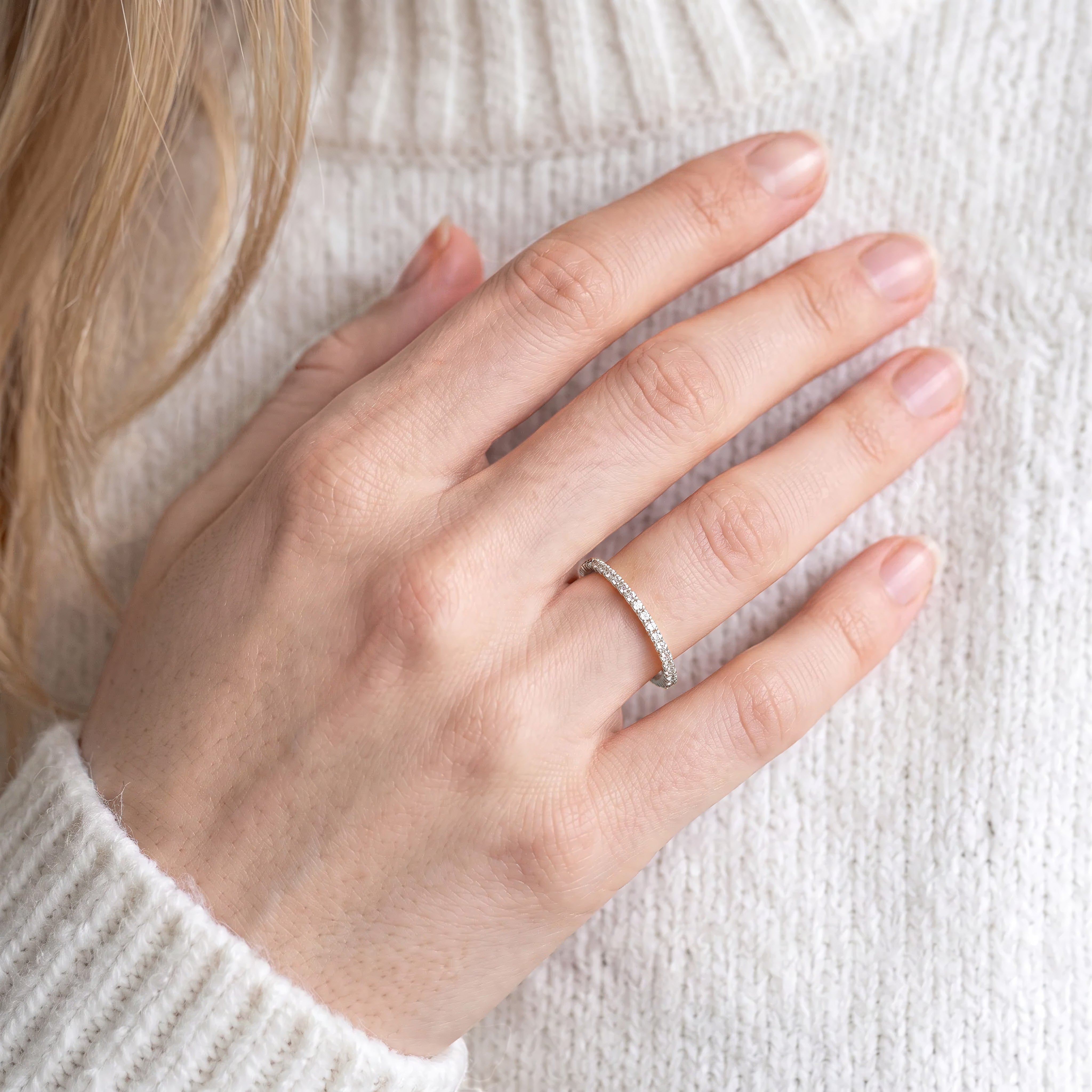 Woman wearing DEMAIN Diamonds Platinum eternity band ring set with lab grown diamonds on ring finger - lifestyle view